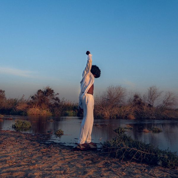 Person stretching outdoors with a serene landscape background.